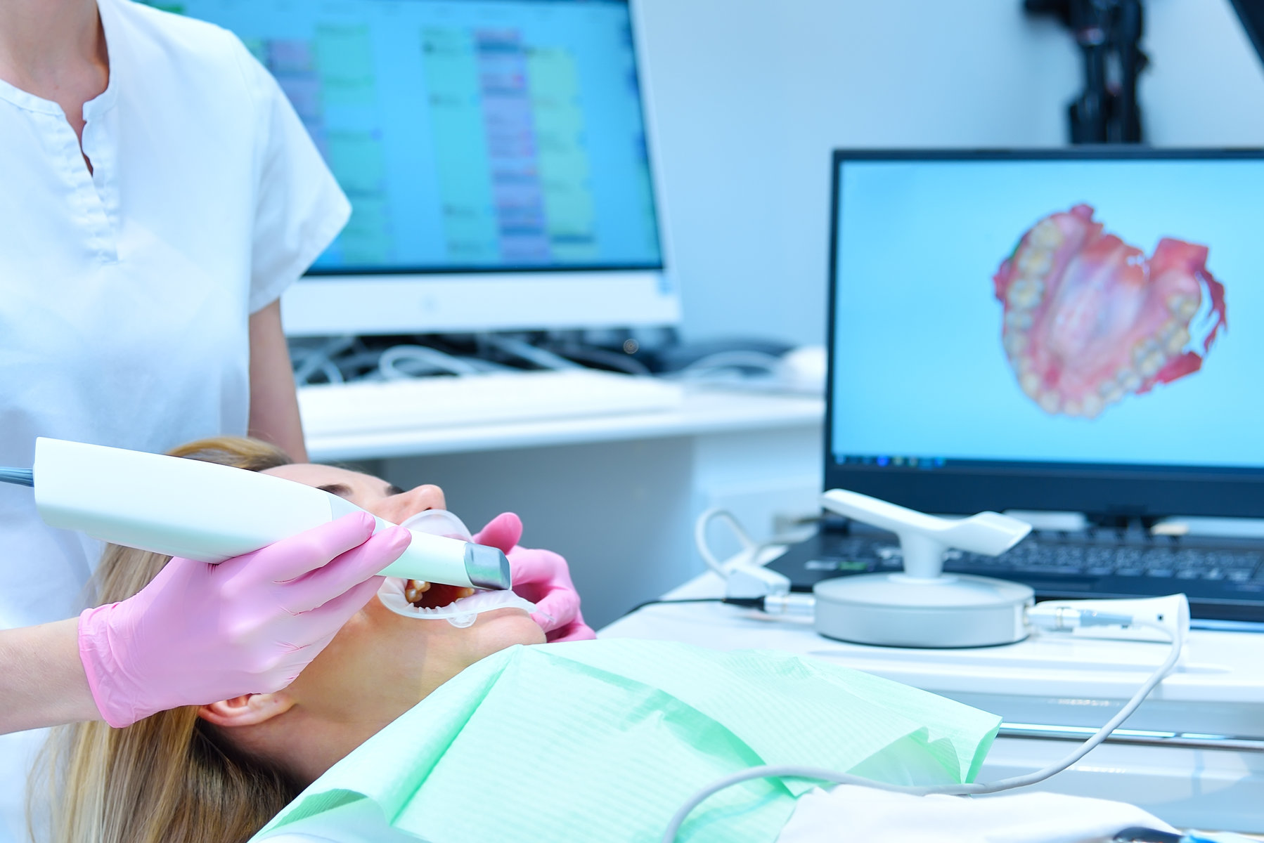 Woman dentist scaning patient's teeth with dental 3d scanner and laptop screen with 3d scanning of jaw. Healthcare and stomatology ñoncept