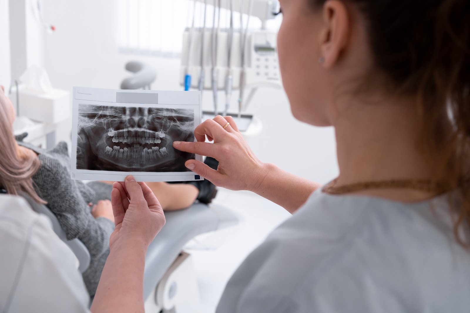 Dentist reviewing a dental X-ray with a patient to diagnose jaw and TMJ pain